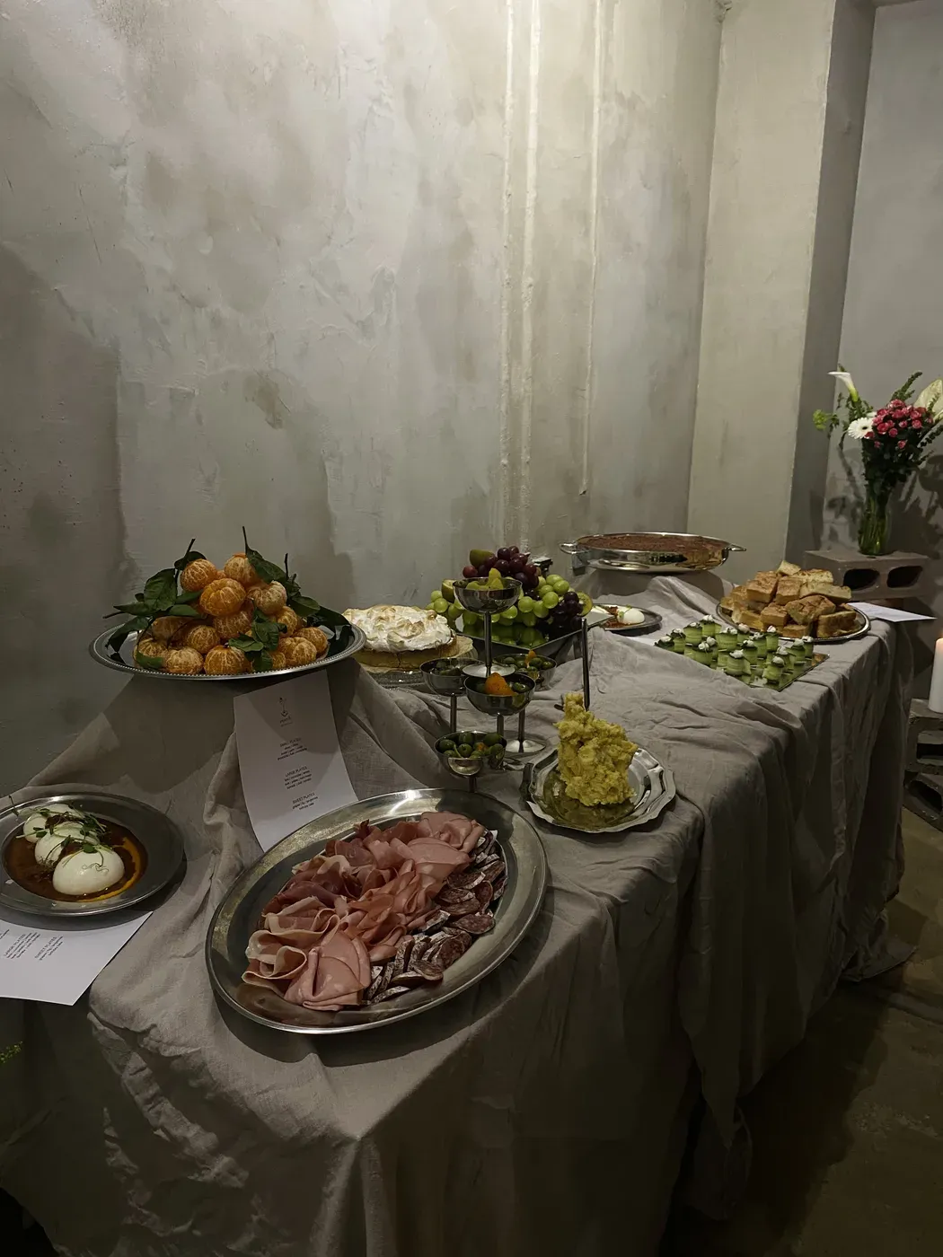 A catering spread with charcuterie, pavlova, and seasonal dishes