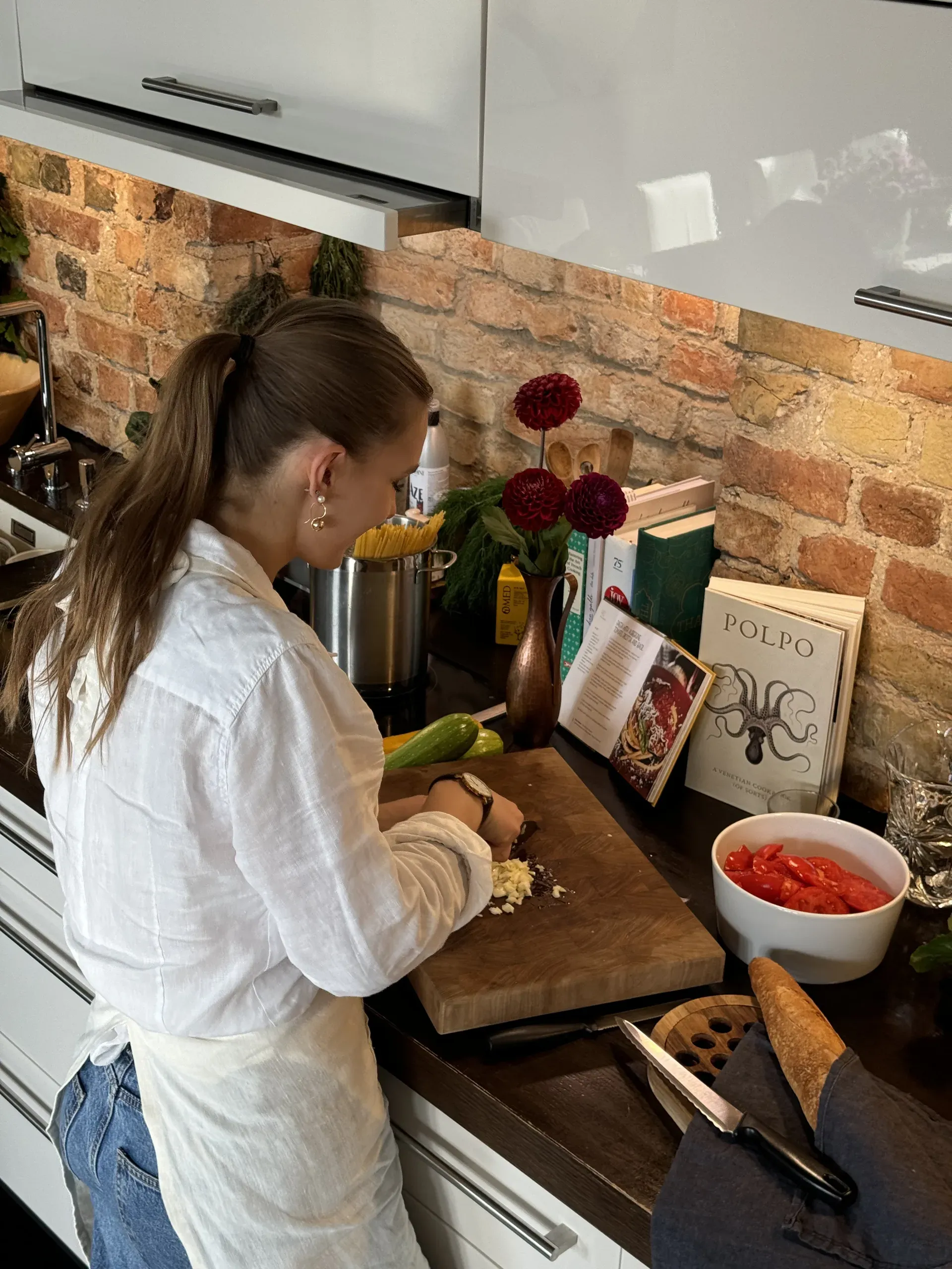 Līva preparing ingredients in the kitchen with cookbooks and fresh produce